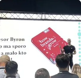 Adam Jędrychowski na scenie podczas prelekcji o marketingu